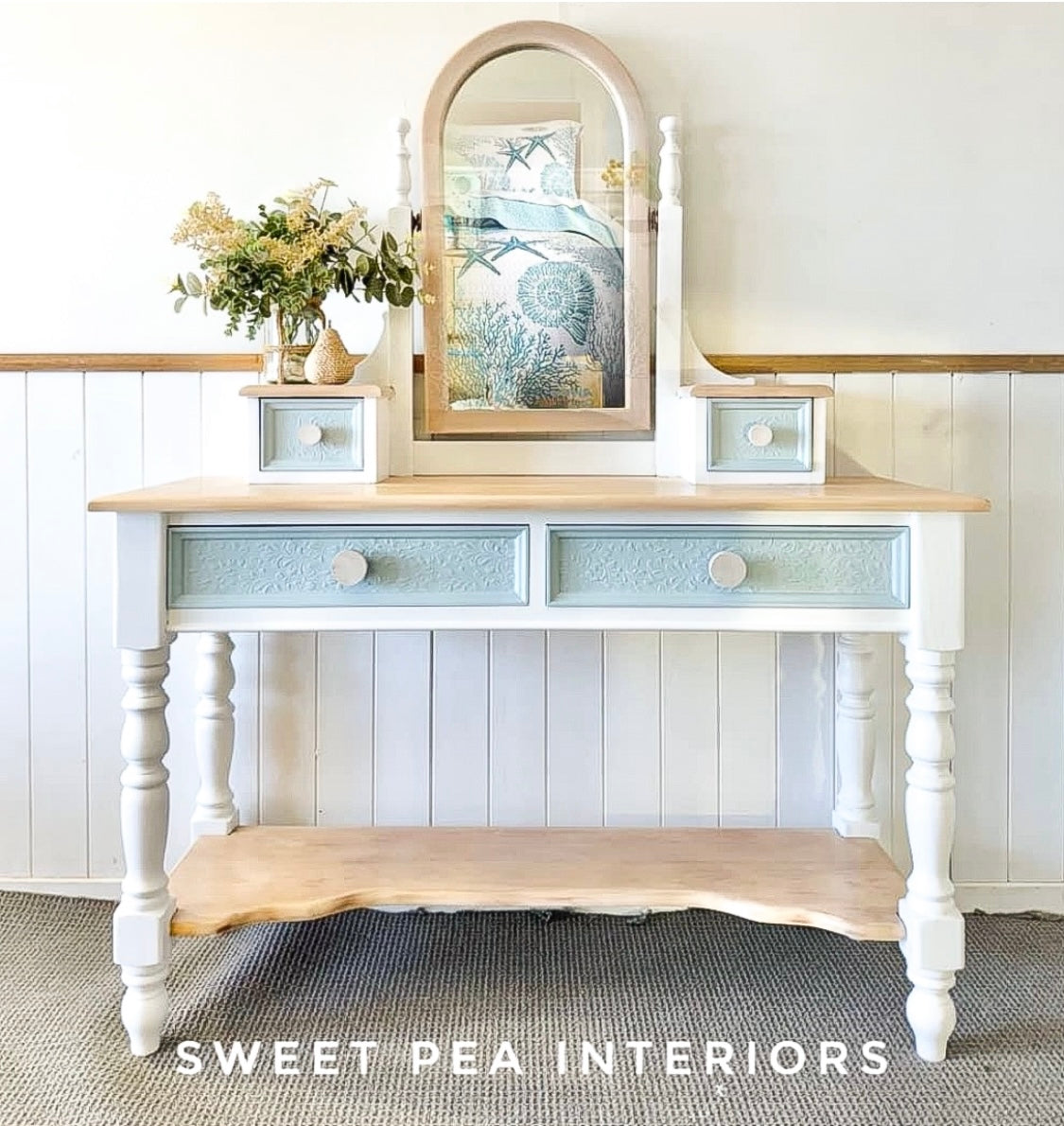 blue and white coastal style dressing table with raw unfinished wooden drawer knobs against white wall 