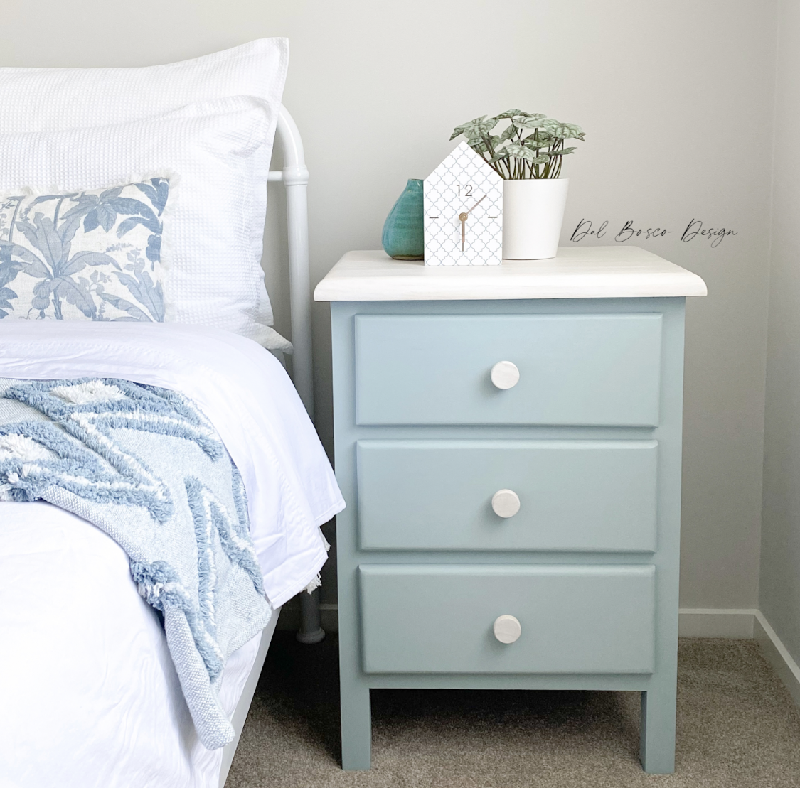 beautiful coastal bedroom featuring nicely made bed and upcycled  soft blue bedside table using raw wooden whitewashed drawer knobs