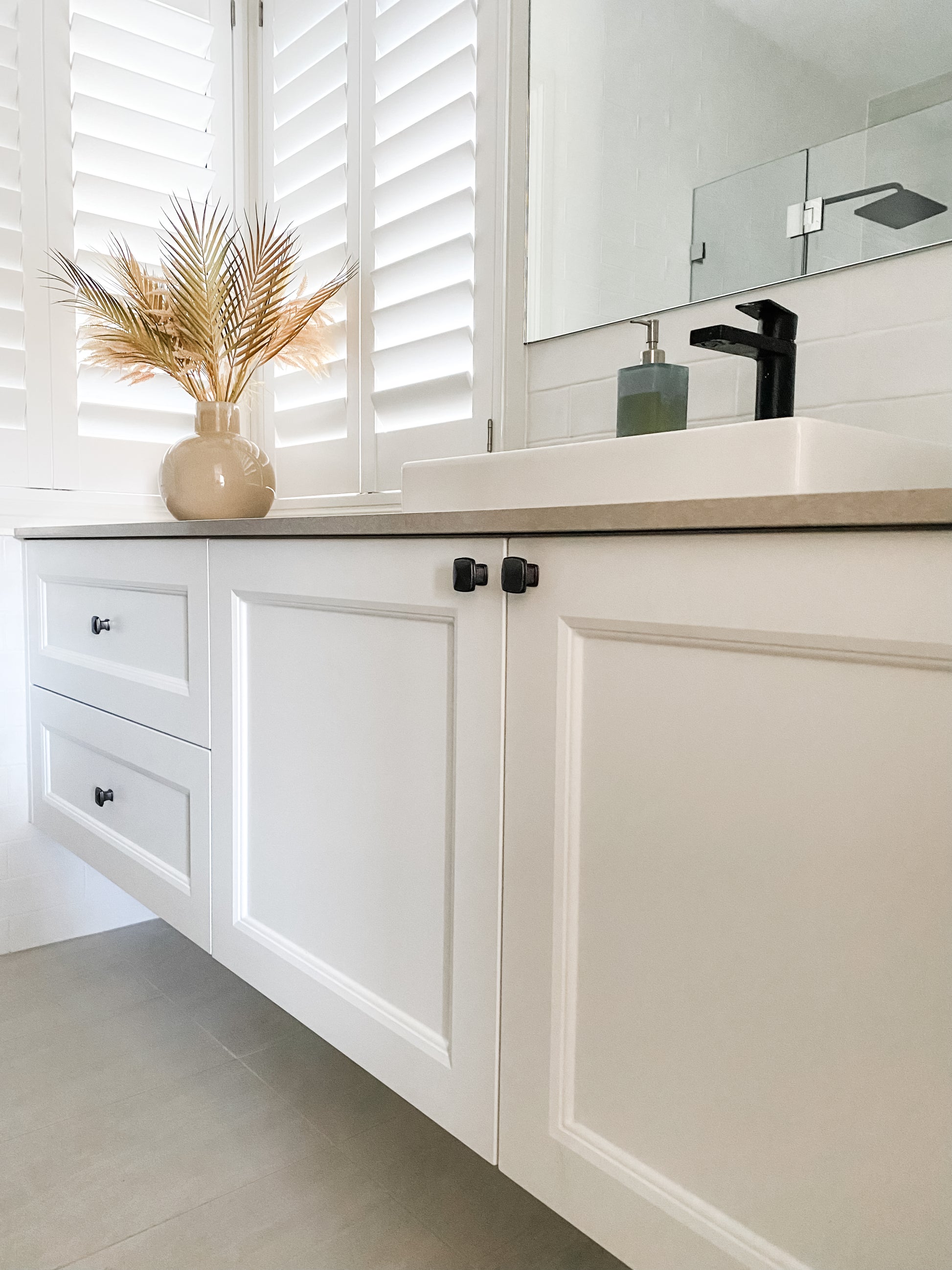 beautiful bathroom with white cupboard doors and black hardware including black square shaped drawer handles