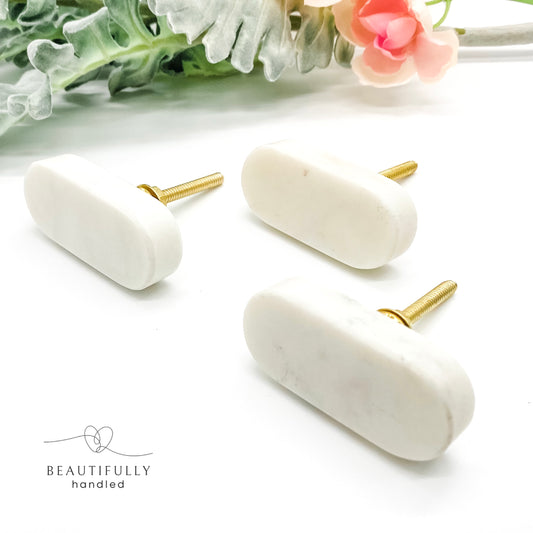 3 marble drawer handles with brass bolts on plain white background