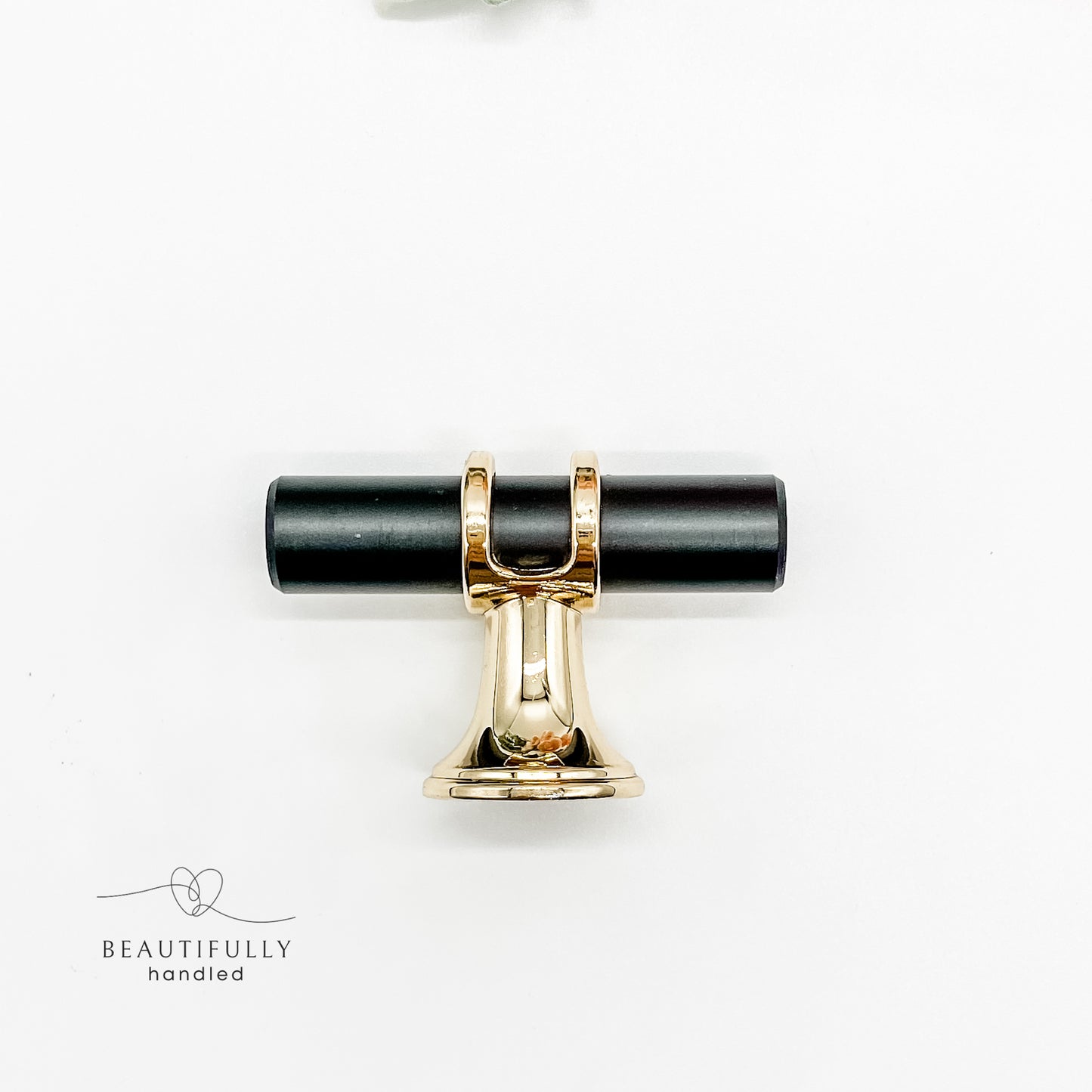 close up of side angle of black and gold metal drawer handle in small 5cm size t bar on white background