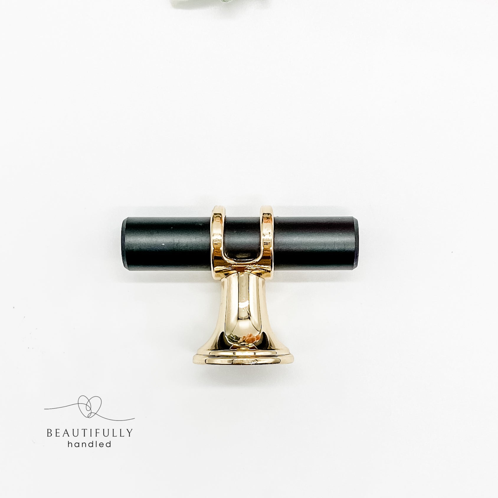 close up of side angle of black and gold metal drawer handle in small 5cm size t bar on white background