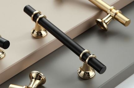 black drawer kitchen handle with gold handle in background laying on cupboard doors 