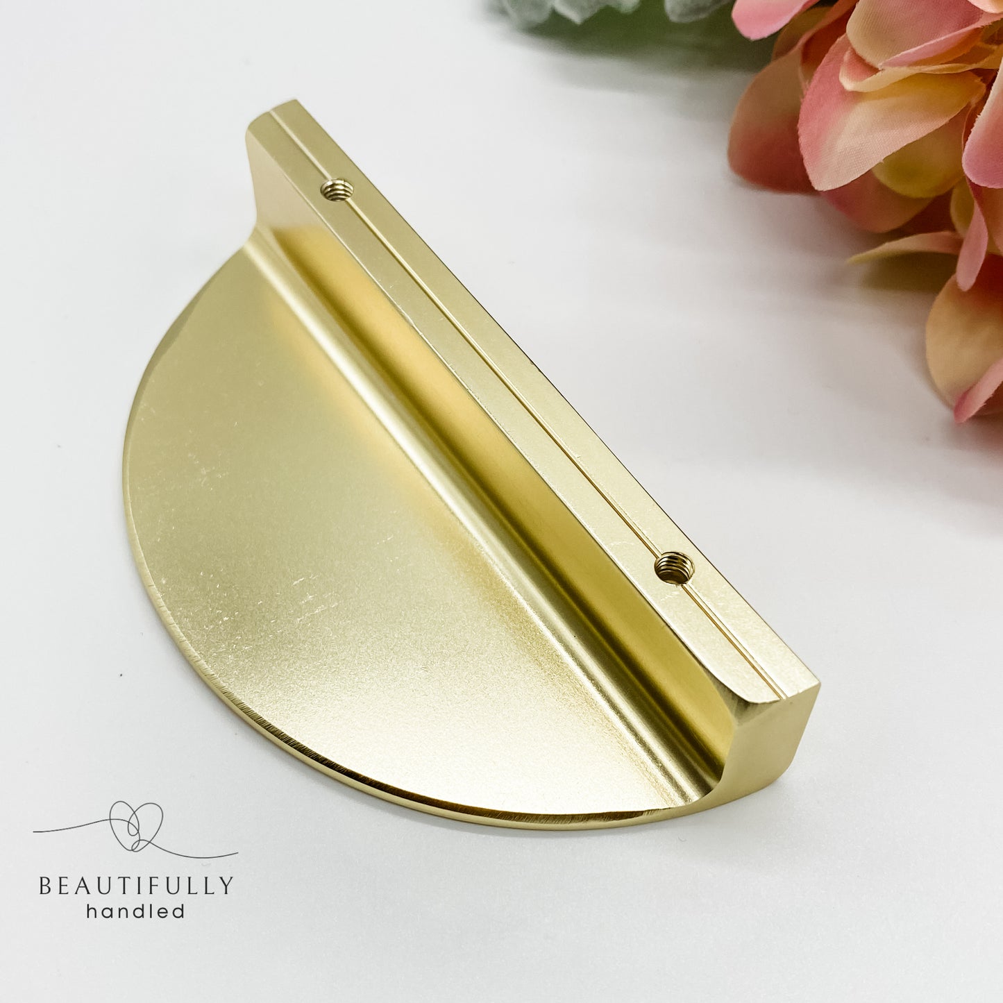 underneath angle of gold half moon drawer handle on plain white background 64mm between holes