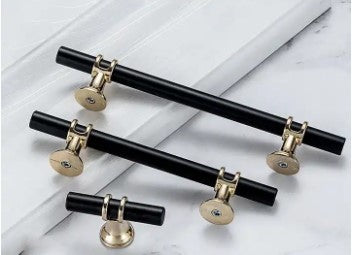 3 different sizes of black drawer handles with gold trim on white kitchen door