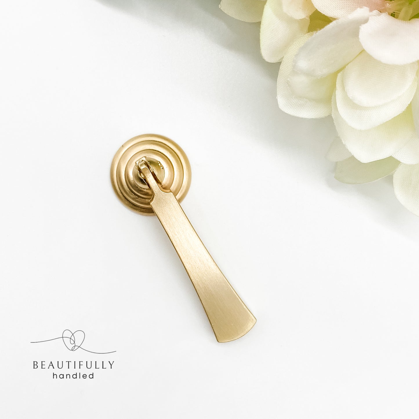 gold drawer handle with drop pull in brushed gold on white background